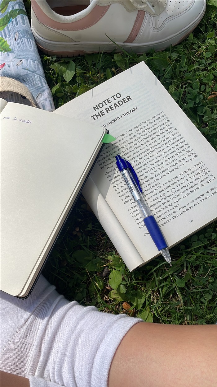 Livro, caderno aberto e caneta sobre a grama